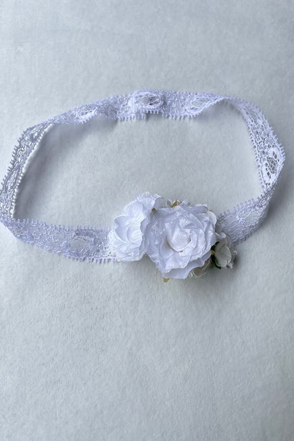 Bandeau cheveux pour bébé fille en dentelle et fleurs blanches. A porter pour un baptême ou une cérémonie. Photo des fleurs du bandeau.