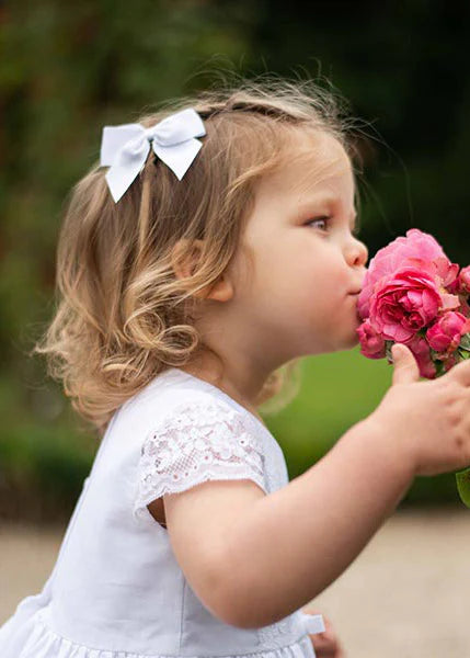 Pince cheveux noeud en gros grain blanc pour petite fille. Parfait pour sublimer une robe de cérémonie pour enfant. Photo de la barrette portée par une petite fille.