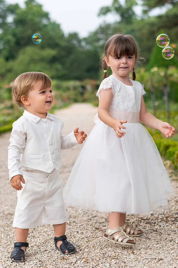 Bermuda cérémonie bébé garçon Oscar en coton blanc cassé. Création française Fil de Légende. Photo d'un bébé garçon avec le bermuda et d'une petite fille habillée en robe de cérémonie.