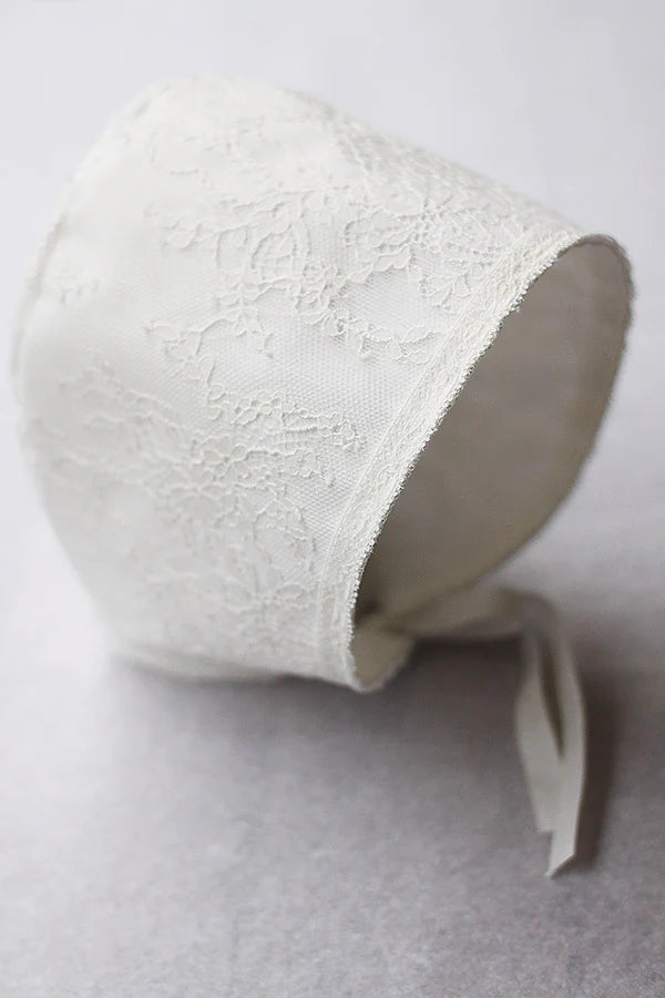 Bonnet de baptême bébé fille Aurélia en dentelle italienne blanc cassé doublé coton. Création française Fil de Légende.  Photo du bonnet vu de côté.
