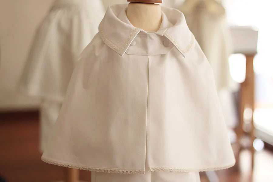 Cape de baptême bébé garçon Oscar en coton blanc cassé et galons de dentelle de coton. Création française Fil de Légende. Photo de la cape sur un mannequin de couture.