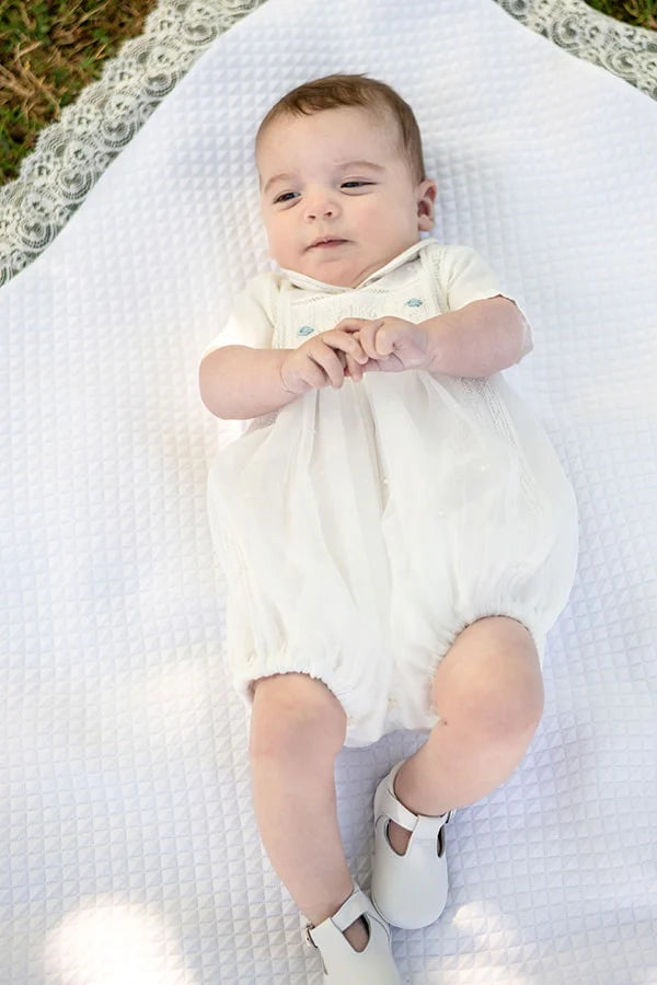 Chaussons baptême cérémonie bébé fille ou garçon pour l'été. Chaussons en cuir blanc avec une ouverture à boucle. Photo des chaussons portés sur bébé.