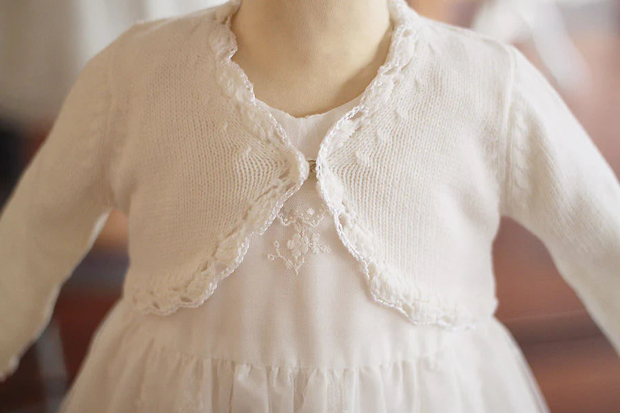 Gilet de cérémonie bébé fille en laine blanc cassé. Idéal avec robe de cérémonie bébé. Photo du gros plan du gilet.