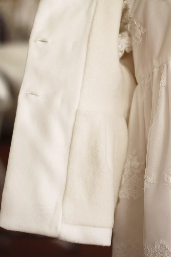 Cape de baptême automne hiver pour fille ou garçon en Mouflon blanc cassé doublé polaire. Fermeture avec boutons. Création française Fil de Légende.  Photo  de l'intérieur du manteau. 