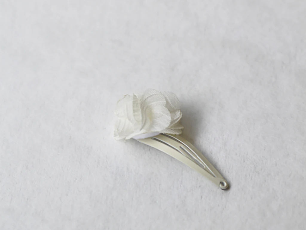 Pince cheveux bébé fille avec fleur en tissu blanc cassé. Parfait pour sublimer la coiffure d'un enfant à l'occasion d'une cérémonie. Photo de la pince cheveux vue de côté.