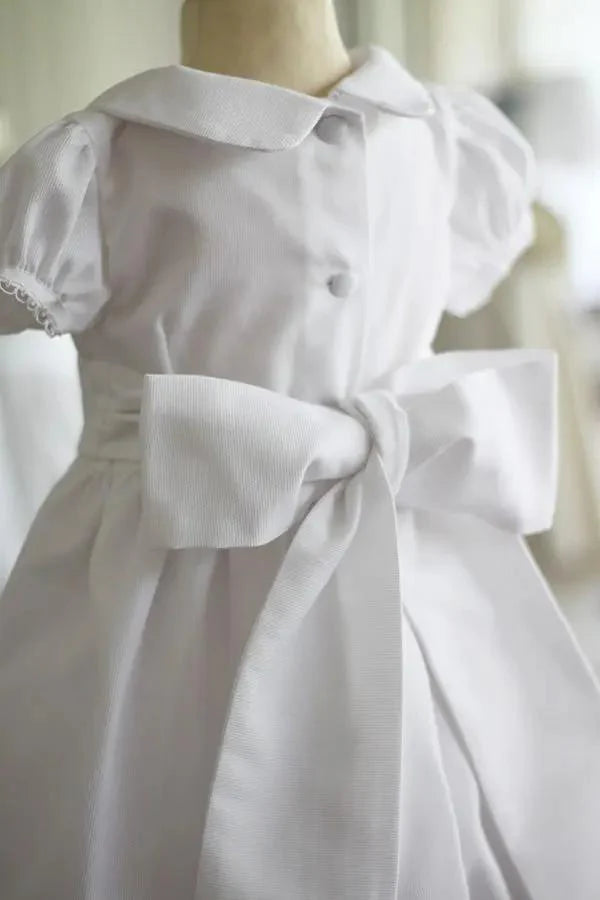Robe de baptême et de cérémonie pour bébé et petite fille, en piqué de coton blanc et dentelle de coton. Ceinture au choix blanche ou rose. Création française Fil de Légende. Photo de la ceinture blanche.
