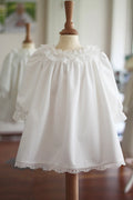 Robe de baptême fille pour l'hiver en velours blanc cassé et dentelle, doublée polaire. Création française Fil de Légende. Disponible en ligne et en boutique showroom Paris, Neuilly-sur-Seine.