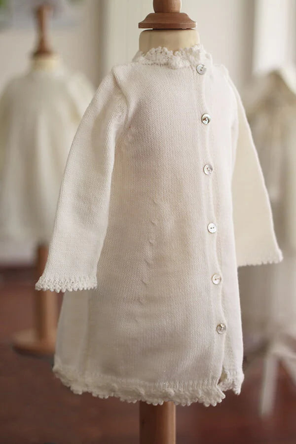 Robe baptême fille blanc cassé en maille tricotée avec bordures faites au crochet à la main. Robe en lainage. Création française Fil de Légende. Photo du dos de la robe.