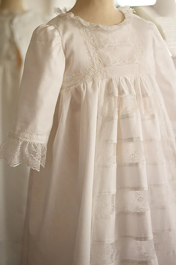 Robe de baptême traditionnelle bébé en coton et dentelle de Calais blanc cassé. Modèle manches longues. Création française Fil de Légende. Photo de la robe vue de côté.