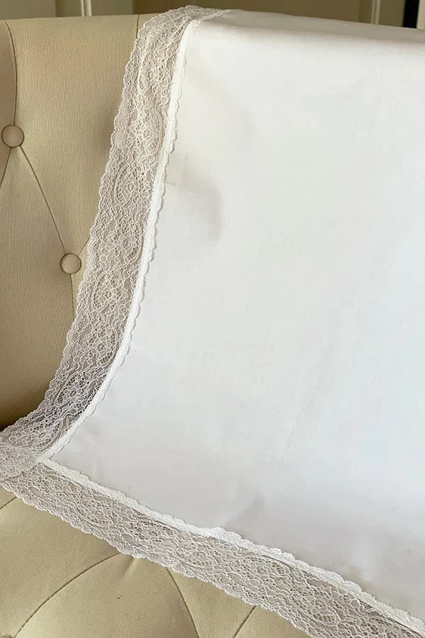 Serviette de baptême en coton blanc bordée d'un large galon de dentelle italienne blanche. Vue de côté.